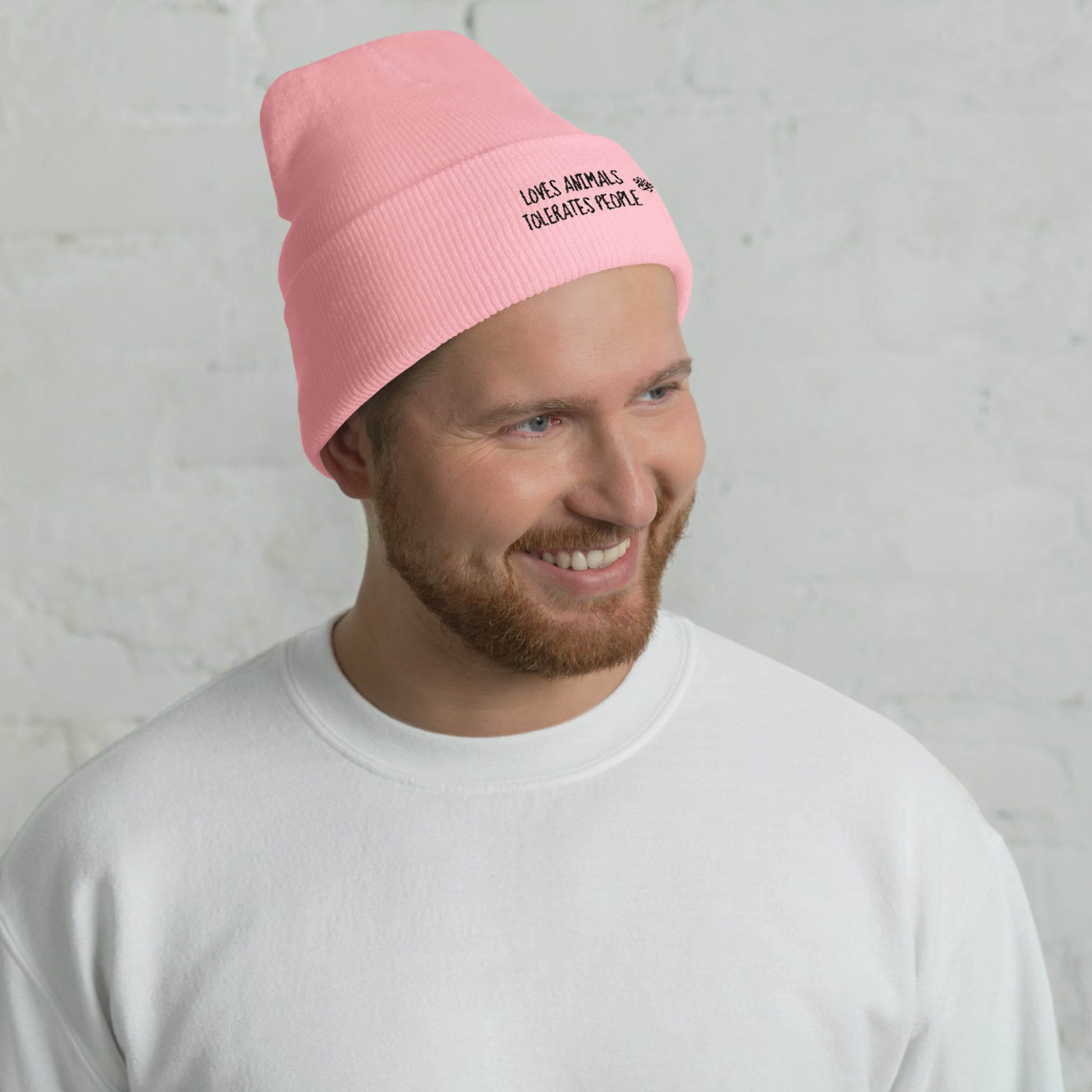 Guy with pink cuffed beanie with black loves animals tolerates people embroidery