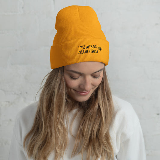 Girl with orange cuffed beanie with black loves animals tolerates people embroidery