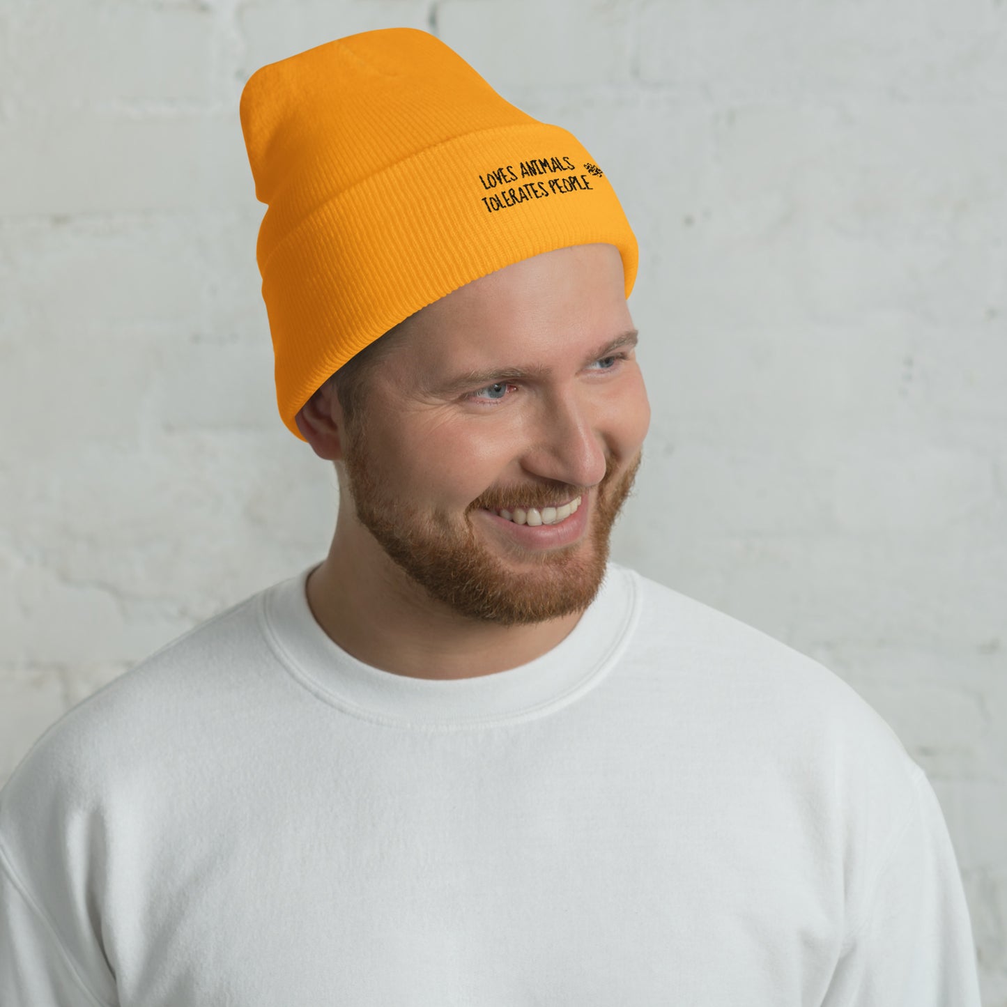 Guy with orange cuffed beanie with black loves animals tolerates people embroidery